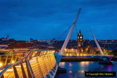 Modern Peace Bridge in Derry over the River Foyle at Night - Twilight with Guildhall and Old Town Cityscape in the background. Derry (also called Londonderry), Northern Ireland, Europe