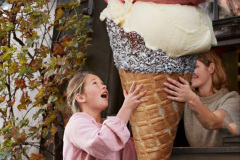 Girl buying large ice cream cone from take out counter of cafe