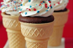 Three cup cakes in ice cream cones (focus on single cone)